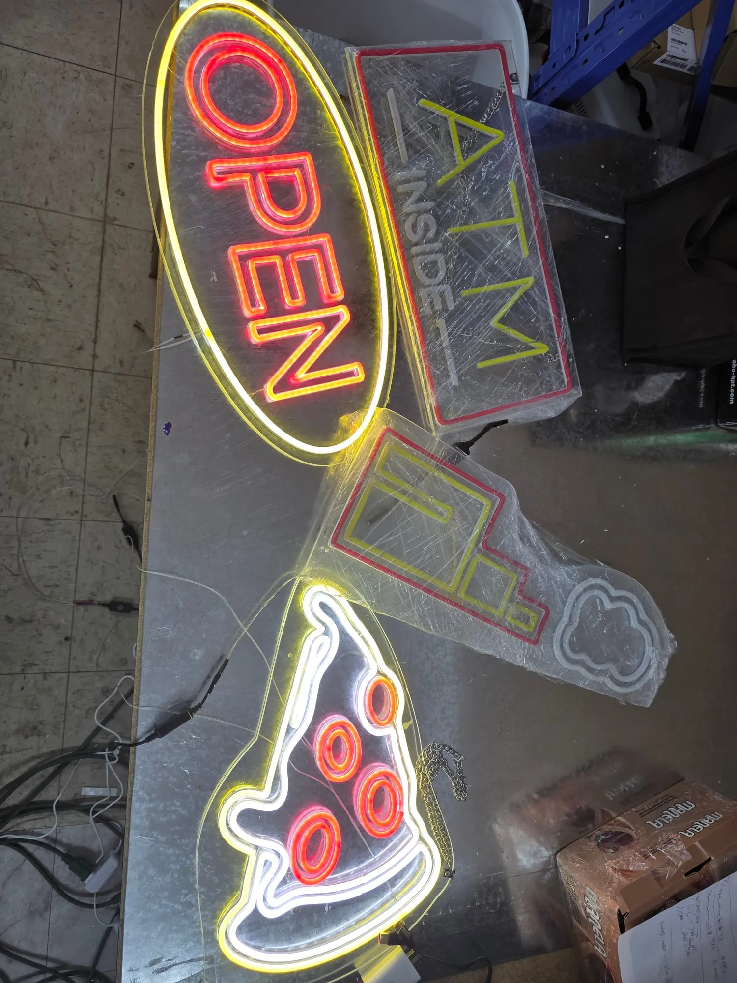 A second overhead view of the open, ATM and pizza signs with the pizza slice at the bottom.