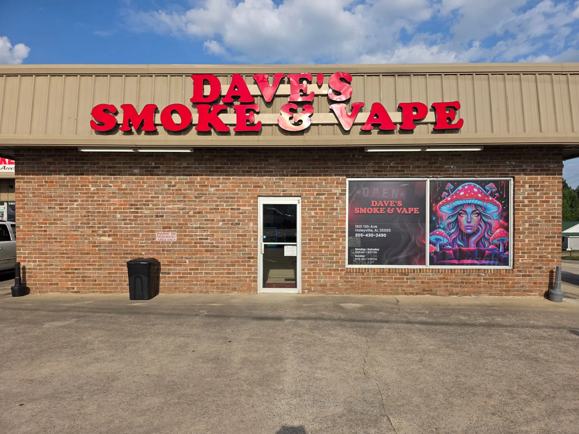 Straight-on view of the same brick storefront with the red letters above, a glass door and a two-panel window poster.